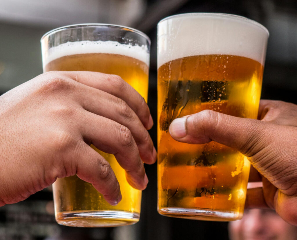 Closeup photo of two beer glasses clinking together